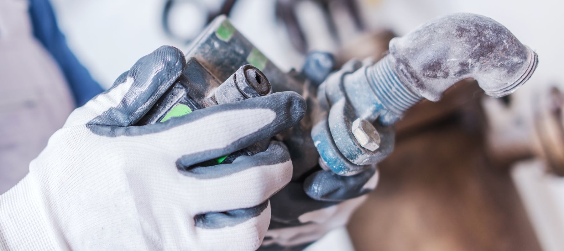 Plumber’s gloved hands holding a corroded pipe fitting
